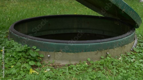 Hands opening green wastewater treatment system cover outdoors