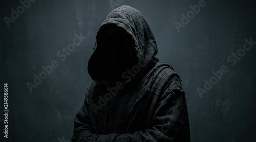 A mysterious hooded figure standing in the shadows creating a dark and ominous atmosphere perfect for a spooky halloween celebration theme