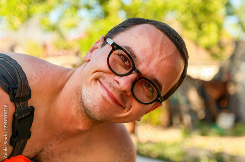 Foto Close-up portrait of a smiling young man wearing stylish glasses outdoors on a sunny day