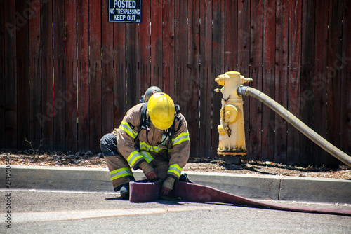 Firemen and women practicing to put out fires on an abandoned house looking at water hydrant for fire access to water to put out fires with a fire fighter hooking up the hose