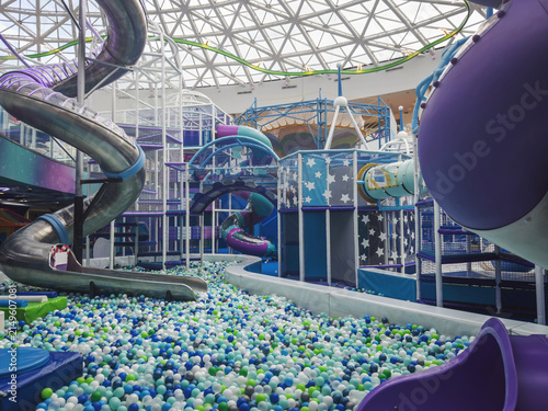 Indoor playground filled with colorful balls, slides, tunnels, climbing structures, soft play equipment, bright interior, family recreation, active children, entertainment, leisure concept