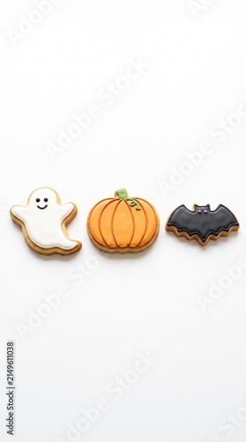 Three festive Halloween cookies a ghost pumpkin and bat decorated with icing on a white background