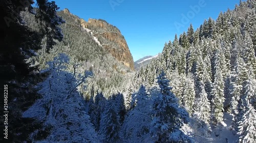 Aerial drone view captures snow covered Sumela Monastery clinging to steep rocky mountain cliff.