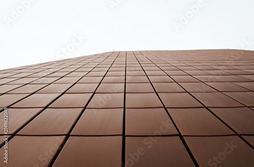 Abstract view of a brown tiled building facade against a white sky