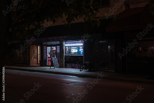Фотография Pedestrians gather outside a brightly lit convenience store at night
