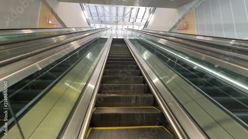 Moving up on a modern long escalator inside a transit station corridor.