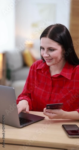 Online store. Woman with credit card using laptop at wooden table indoors