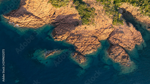 Top down aerial view of red volcanic cliffs and crystal-clear Mediterranean waters in the Esterel Massif, France