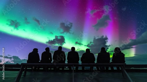 Group watching colorful Aurora Borealis dance in starlit sky