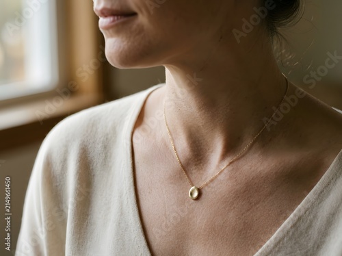 Close-up of woman wearing delicate gold pendant necklace, quiet luxury jewelry
