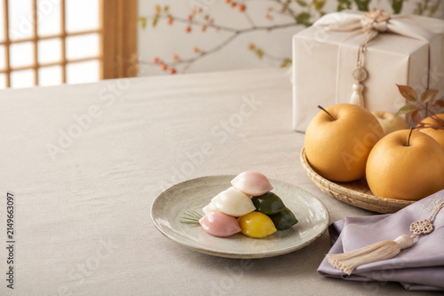Korean harvest table setting with songpyeon, ripe pears, hanbok fabric napkin, and gift box, Chuseok celebration concept