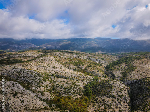 Rugged Limestone Karst Landscape with Scattered Green Vegetation Under Cloudy Sky