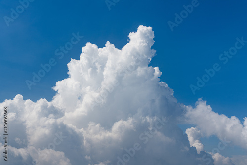 Fotografía stunning view of a towering white fluffy cloud formation drifting across a clear deep blue sky on a bright sunny afternoon, perfect for travel themes