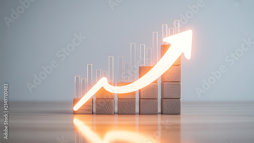 A glowing upward arrow overlays a bar chart made of wooden blocks against a grey.