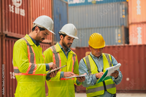 Fotografie Worker hardhat safety vest clipboard container logistics shipping inspection por