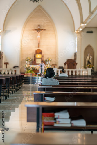 Fotografie Person praying in a serene church interior with wooden pews