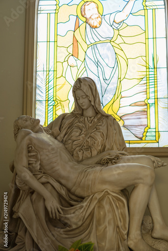 Fotografie Religious sculpture of Mary holding Jesus with stained glass background