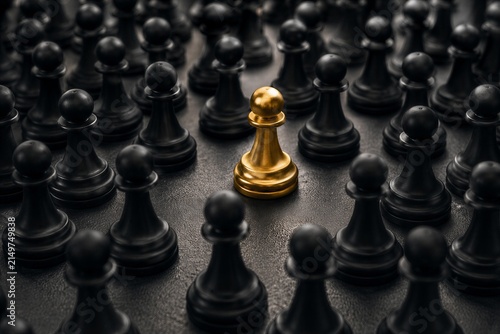 Gold chess pawn among black pawns representing leadership, competition, and standing out from the crowd