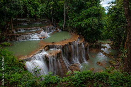 A waterfall cascading down over large limestone formations in the forest.