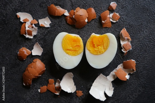 Obraz na płótnie This photo shows a hard-boiled egg cut in half, surrounded by the brown eggshells that have been peeled off