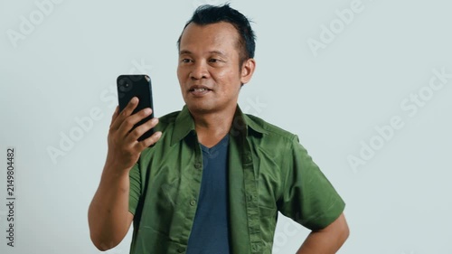 Video call. Portrait of man talking on smartphone or using virtual personal assistant app on his device. 
Asian man recording video call with mobile phone.