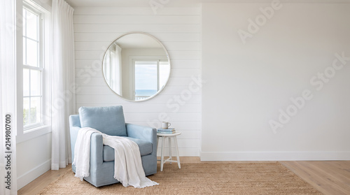 Bright coastal bedroom corner with blue armchair and ocean view mirror