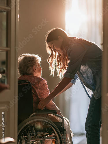 Older adult caregiver adjusting wheelchair in home care with warm sunlight and gentle support