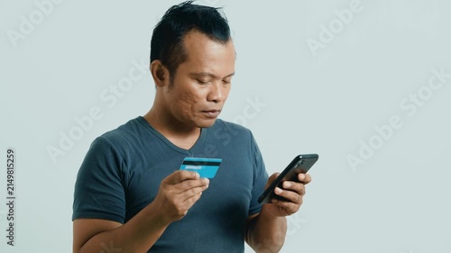 Asian man have online shopping on mobile phone with credit card isolated on white. 4K video footage advertisement.