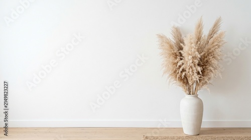 Minimalist interior decor of fluffy pampas grass in white ceramic vase on wooden floor