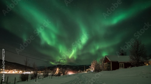 Vibrant aurora borealis illuminating snowy rural landscape at night
