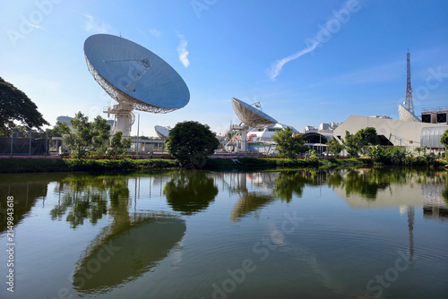 Satellite dish antenna stations with skyline reflection on pond