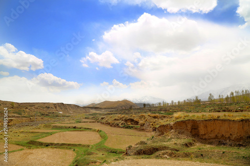 Fotografie Agricultural Valley with Water Irrigation Channels and Snow Mountains