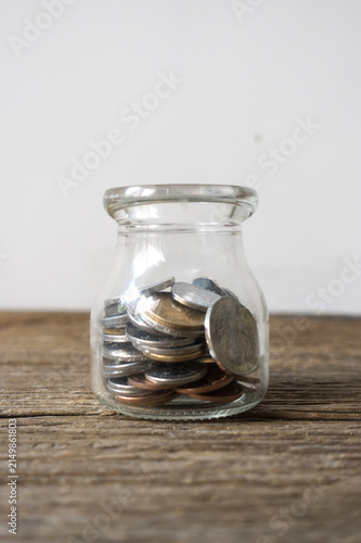 Картината върху платно Glass Jar of Mixed Coins on Rustic Wooden Table