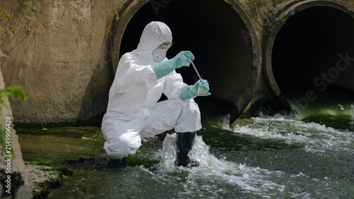 Konstfotografi Scientist in Hazmat Suit Sampling Polluted Water with Pipette by Drainage