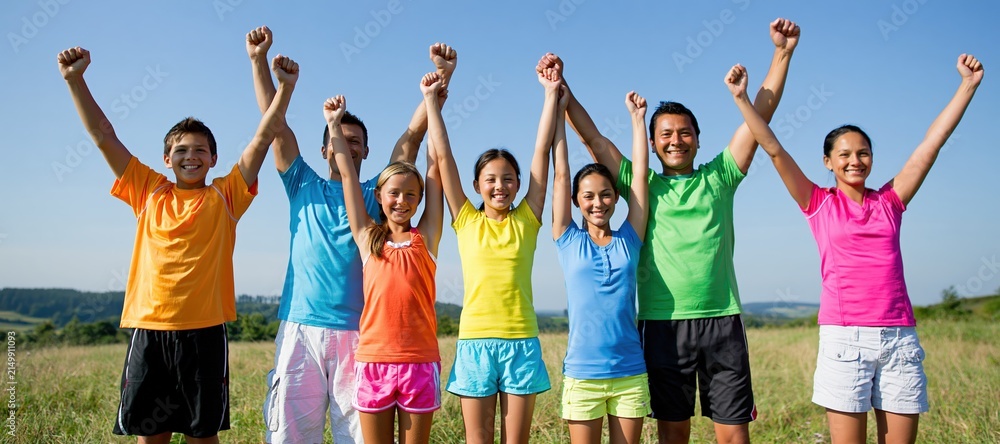 Fototapeta premium Family celebrating running achievement with raised arms in summer meadow