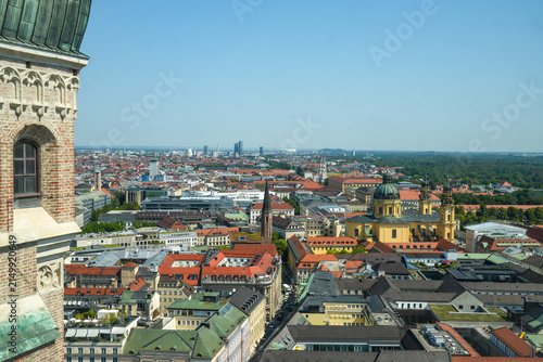 Aerial view of Munich featuring the striking yellow Theatine Church, Odeonsplatz, and the English Garden on the horizon. Taken from the tower of the Frauenkirche on a sunny summer day.