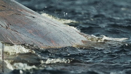 Waves roll onto the gently sloping rocky shore in slow motion