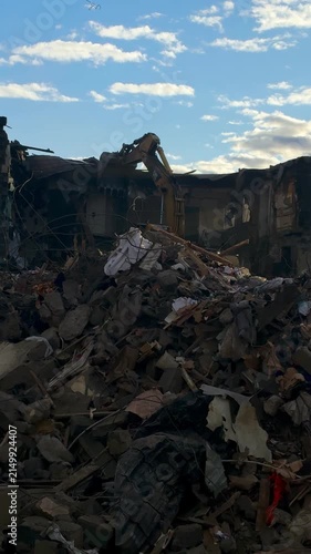 A large pile of rubble and broken structural debris scattered after a disaster or demolition, showing fragmented materials under a blue sky.