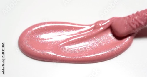 Macro shot of pink liquid lipstick applicator touching a white surface, professional cosmetic product texture and makeup application.