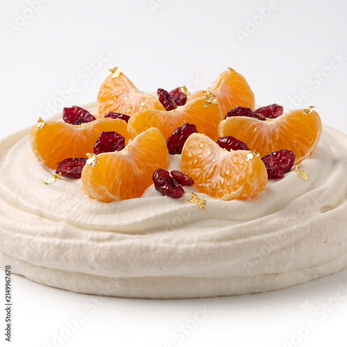 Distant shot of 5 to 10 tangerine segments and dried cranberries resting on thick white citrus whipped cream