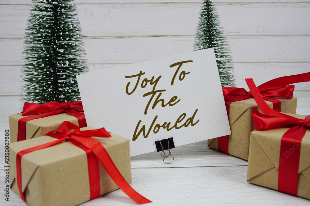 Naklejka premium Joy to the World text written on paper card with gift box and christmas tree