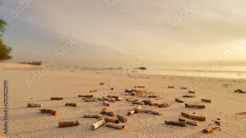 Obraz na plátně cigarette butts pollution on sandy beach, ocean water pollution, environmental i