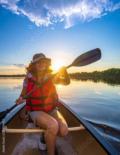 Woman enjoying sunset paddleboarding on lake.