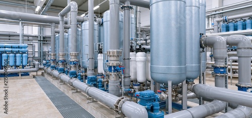 Close-up of industrial water purification system featuring ion exchange columns and activated carbon filters.