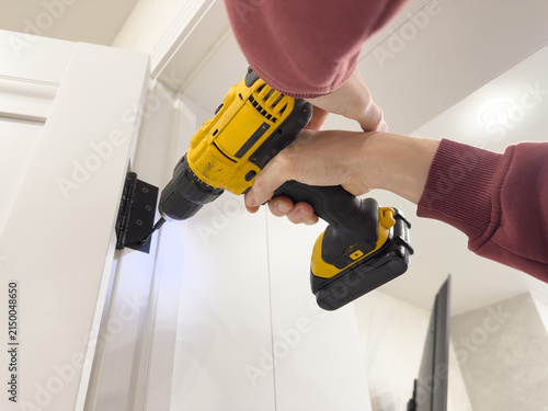 Konstfotografi A Person Using a Power Drill to Install a Door Hinge in a Modern Interior Space