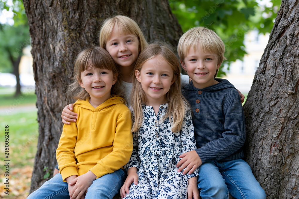 Fototapeta premium Kids smiling and sitting together under a tree
