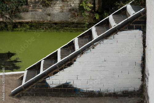 Photography White painted brick stairway leading to green canal water