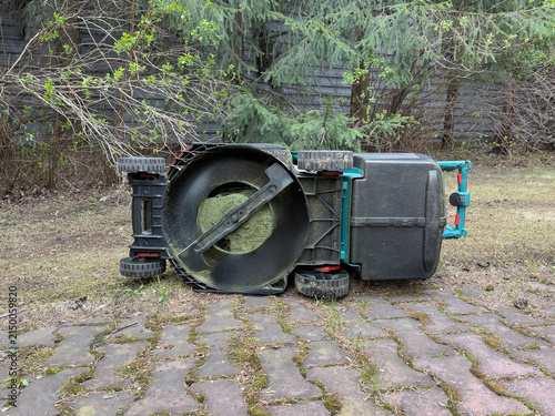 Cuadro en lienzo A Defunct Lawn Mower Lies Upside Down on a Moderately Maintained Garden Path Sur