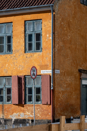 Weathered ochre facade with shuttered windows and street signs in Copenhagen Denmark