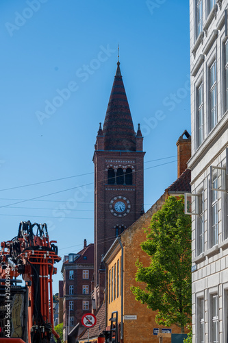 Brick church tower rising above town street with construction crane in Copenhagen Denmark